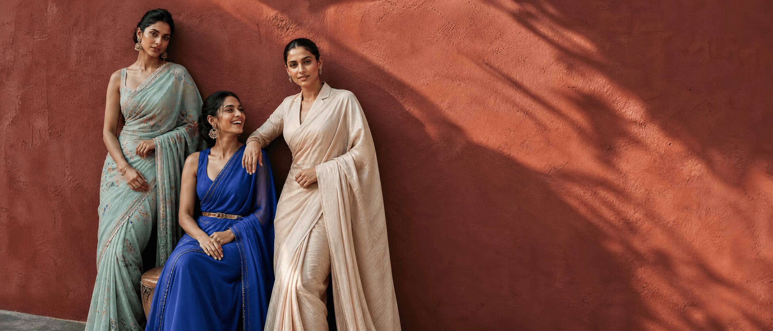 Three women in Nivvi sarees against a terracotta wall